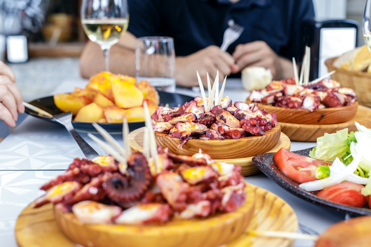 Gente comiendo Pulpo a la Gallega con patatas. Platos de pulpo a la gallega. Platos famosos de Galicia, España.